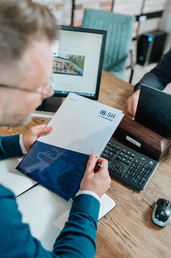 Im Beratungsgespräch wird eine Broschüre der Investitionsbank Schleswig-Holstein besprochen